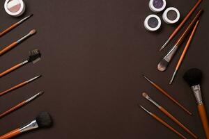 Various cosmetics and brushes on brown background photo