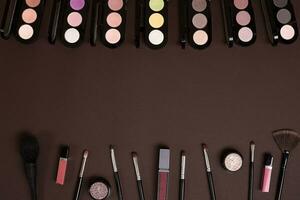 Various cosmetics and brushes on brown background photo