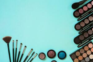 Make up essentials. Set of professional make up brushes, creams and shadows in jars on blue background. photo