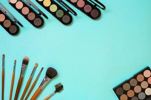 Make up essentials. Set of professional make up brushes, creams and shadows in jars on blue background. photo