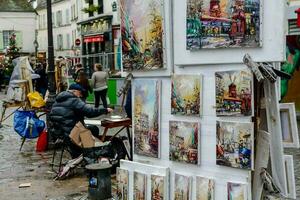 a man is painting on a street corner in front of paintings photo