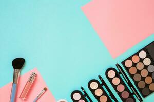 Make up essentials. Set of professional make up brushes, creams and shadows in jars on blue background. photo