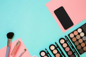 Make up essentials. Set of professional make up brushes, creams and shadows in jars on blue background. photo