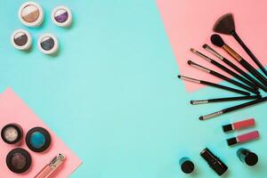 Make up essentials. Set of professional make up brushes, creams and shadows in jars on blue background. photo