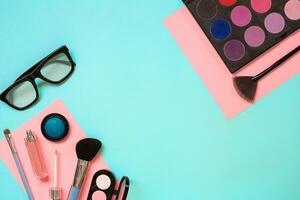 Make up essentials. Set of professional make up brushes, creams and shadows in jars on blue background. photo