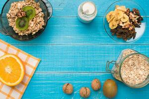 Bowl of fresh oatmeal porridge with kiwi and nuts on teal rustic table photo