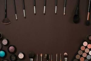 Make up essentials. Set of professional make up brushes, creams and shadows in jars on dark background. photo