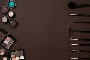 Various cosmetics and brushes on brown background photo