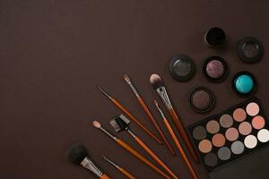 Make up essentials. Set of professional make up brushes, creams and shadows in jars on dark background. photo