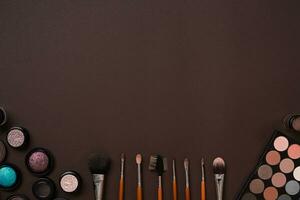 Various cosmetics and brushes on brown background photo