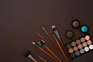 Make up essentials. Set of professional make up brushes, creams and shadows in jars on dark background. photo