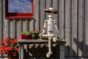 a wooden man sitting on a bench with flowers photo