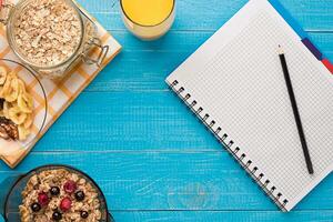 Breakfast with oatmeal and berries in bowl and orange juice in cup. Space for text. photo