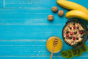 oatmeal porridge with banana, kiwi fruit, nuts and honey in a bowl with egg for healthy breakfast on rustic wooden background. top view photo