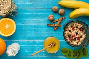 oatmeal porridge with banana, kiwi fruit, nuts and honey in a bowl with egg for healthy breakfast on rustic wooden background. top view photo