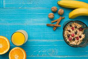 oatmeal porridge with banana, kiwi fruit, nuts and honey in a bowl with egg for healthy breakfast on rustic wooden background. top view photo