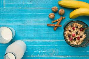 oatmeal porridge with banana, kiwi fruit, nuts and honey in a bowl with egg for healthy breakfast on rustic wooden background. top view photo