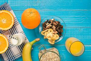 Bowl of fresh oatmeal porridge with banana and nuts on teal rustic table photo