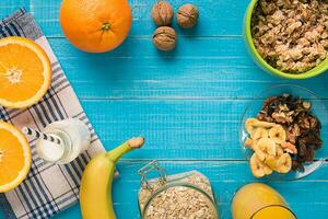 Bowl of fresh oatmeal porridge with banana and nuts on teal rustic table photo