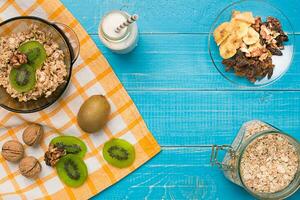 cuenco de Fresco harina de avena gachas de avena con kiwi y nueces en verde azulado rústico mesa foto