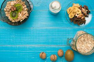 Bowl of fresh oatmeal porridge with kiwi and nuts on teal rustic table photo