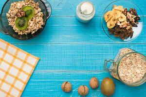 Bowl of fresh oatmeal porridge with kiwi and nuts on teal rustic table photo