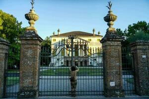 a man standing in front of a gate with a statue in the background photo