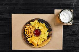 Lager beer and snacks on black wooden table. Nuts, chips. Top view with copyspace photo