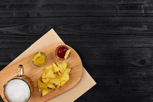 vaso de cerveza con nachos papas fritas en un de madera antecedentes. foto