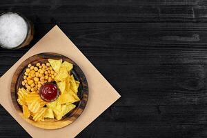 Lager beer and snacks on black wooden table. Nuts, chips. Top view with copyspace photo