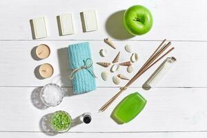 Spa set with sea salt, essential oil, soap and towel decorated with seashells on white wooden background photo