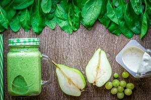 Healthy green smoothie with spinach in a mug against on wooden background photo