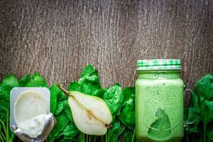 Glass of spinach juice on wooden background photo