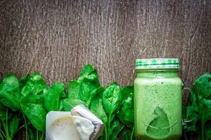 Glass of spinach juice on wooden background photo