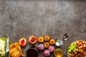 Oatmeal with plums and peach, toast with butter and honey on a wooden table. The concept of a healthy breakfast photo