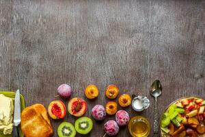 Oatmeal with plums, kiwi and peach, toast with butter and honey on a wooden table. The concept of a healthy breakfast photo