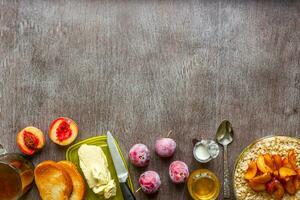 Oatmeal with plums and peach, toast with butter and honey on a wooden table. The concept of a healthy breakfast photo