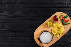 Glass of beer with nachos chips on a wooden background. photo