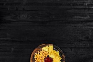 Overhead view of snacks with sauce on black wooden table. photo