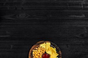 Overhead view of snacks with sauce on black wooden table. photo