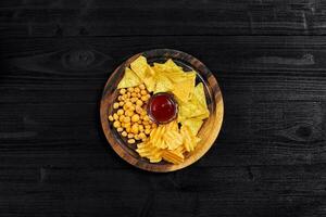 Overhead view of snacks with sauce on black wooden table. photo