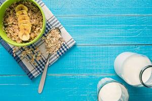 healthy breakfast with bowl of homemade oatmeal with fruits and milk over rustic wooden background. photo