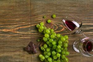 Glasses of wine and ripe grapes isolated on a wooden table photo