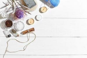 Spa set with sea salt, essential oil, soap and towel decorated with dry flower on white wooden background photo