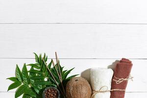 SPA still life with towel, candles and green leaves on a white wooden surface photo