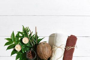 SPA still life with towel, candles and green leaves on a white wooden surface photo