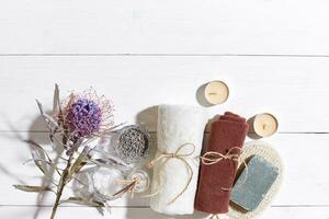 Spa set with soap and towel decorated with dry flower on white wooden background photo