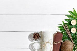 SPA still life with towel, candles and green leaves on a white wooden surface photo