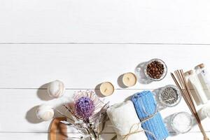 Spa set with sea salt, essential oil, soap and towel decorated with dry flower on white wooden background photo