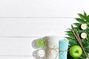 SPA still life with towel, candles and green leaves on a white wooden surface photo